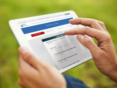 close up on hands touching an iPad to submit a claim while person is on the grass