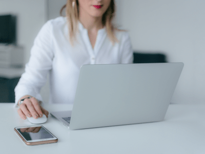 woman in a white office on a laptop using a wireless mouse