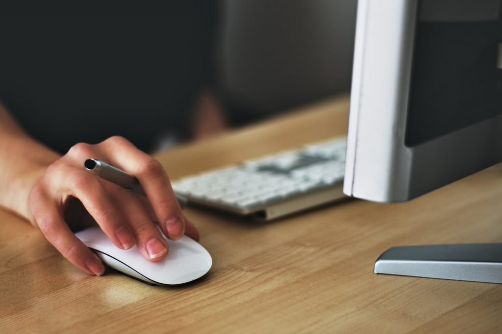 close up on a hand on a wireless mouse while next to a desktop