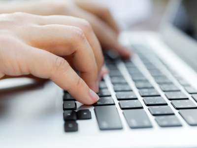 close up of fingers typing on laptop