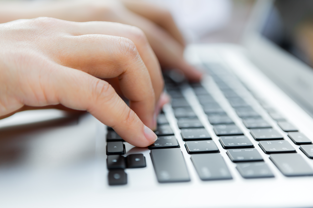 close up of fingers typing on laptop