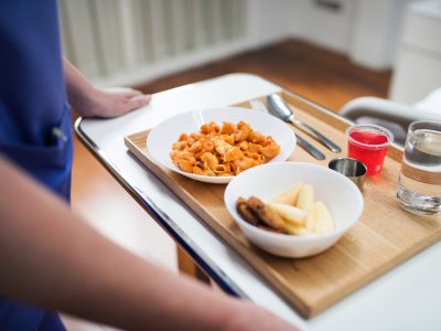 medical aid walking in a tray of food to patient room