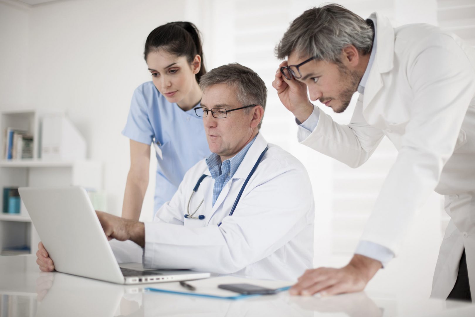 Medical practioners surrounding a laptop