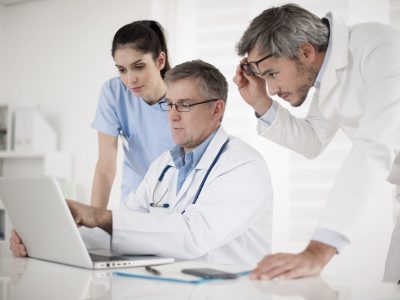 Medical practioners surrounding a laptop