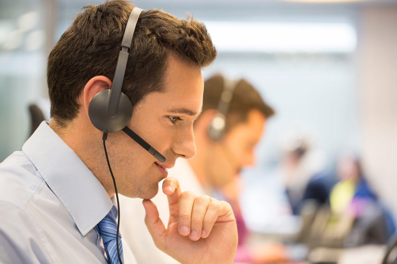 businessman with a phone headset on, assisting his customer over the phone