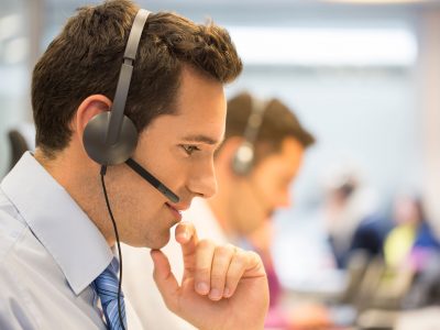 businessman with a phone headset on, assisting his customer over the phone
