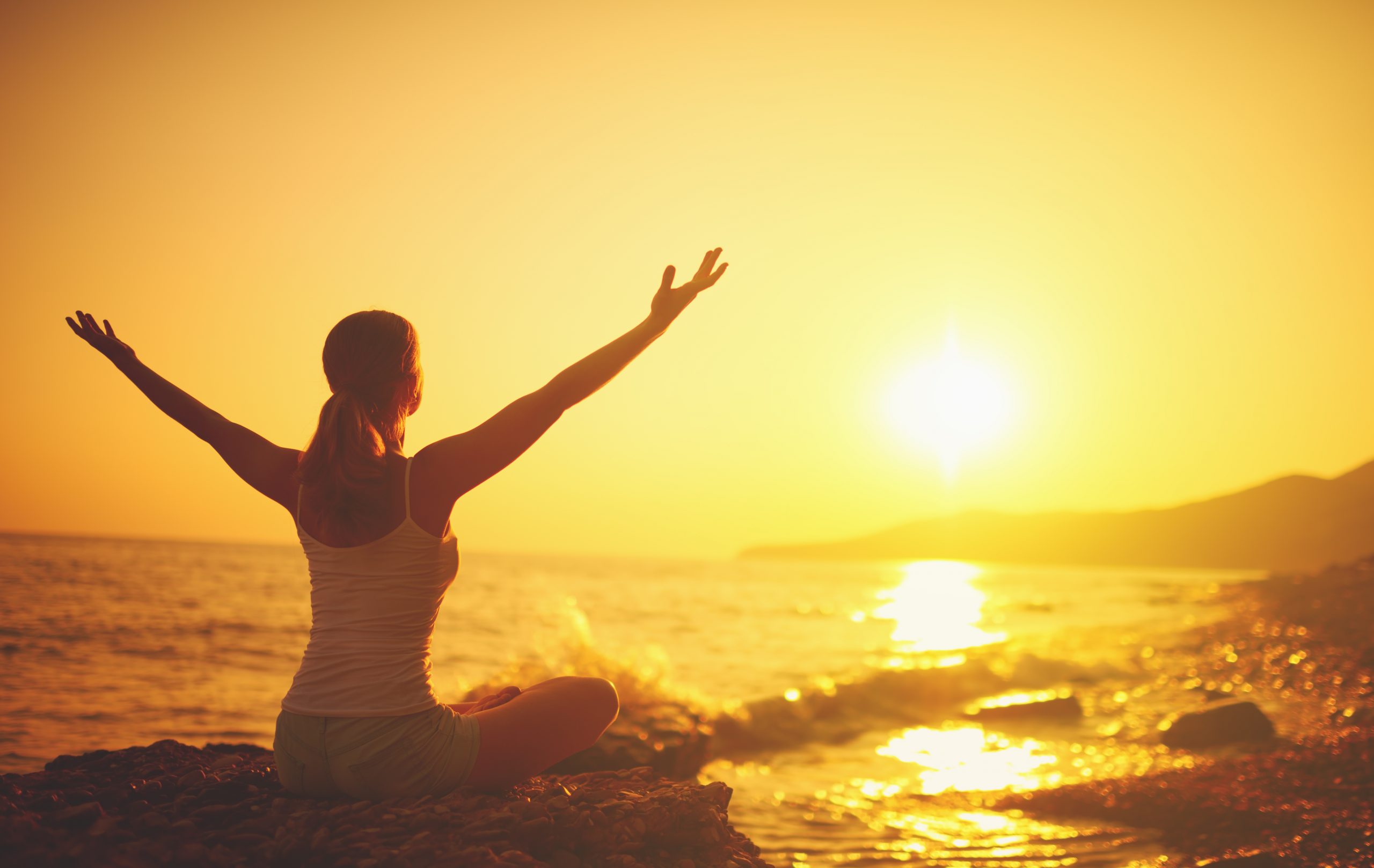 Woman doing yoga on the beach and enjoying her new health habits