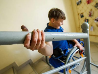 person struggles to descend stairs while in a wheelchair